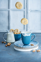 Flying peanut cookies and milk in a blue ceramic mug. Splash and drops of milk. Children's Breakfast concept