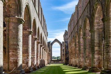 Stone ruins of Fountains Abbey and Studley Royal on a warm, summer day. - obrazy, fototapety, plakaty