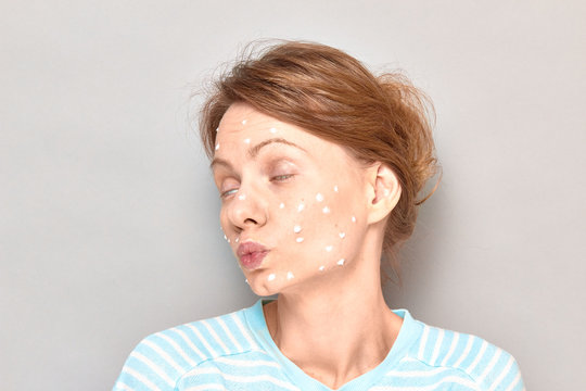 Portrait of funny flirty girl with white drops of face cream on skin