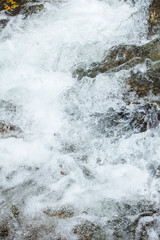 Rapid flowing water in mountain river stream. Foam flow water splash natural waterfall wild nature background


