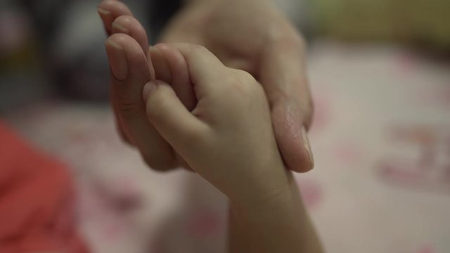 Baby boy holding hand with mother at home 