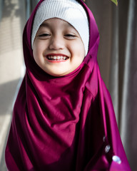 Portrait of a happy muslim toddler girl with hijab. Natural light, selective focus.