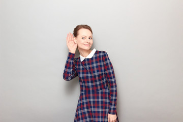 Portrait of young woman placing hand near ear and eavesdropping