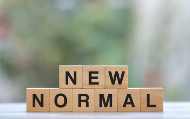 NEW NORMAL word on wooden cube. New normal after covid-19 pandemic with social distancing and good...