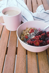 Oatmeal porridge in bowl topped with fresh berry and cup