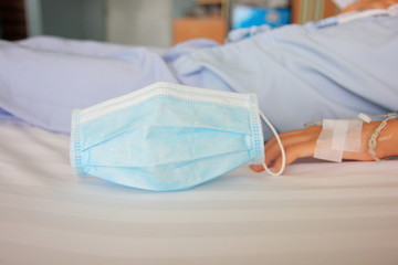 Mask to prevent anti virus save in hospitalization or Everywhere,Mask blue on the whit table and child girl sleep on the bed in hospital.