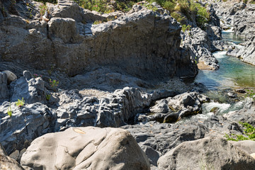 Mountain river with blue water and Volcanic stones around. Gorge of Alcantara on island Sicily in Italy.  Beautiful mountain landscape.