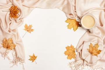 Autumn flat lay with cup coffee cappuccino and yellow autumnal leaves on white wooden background with copy space. Natural leaves of maple tree and cozy warm palantine. Top view.