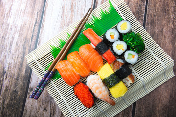 Sushi Set and Japanese Chopstick on Bamboo Plate with Wooden Background