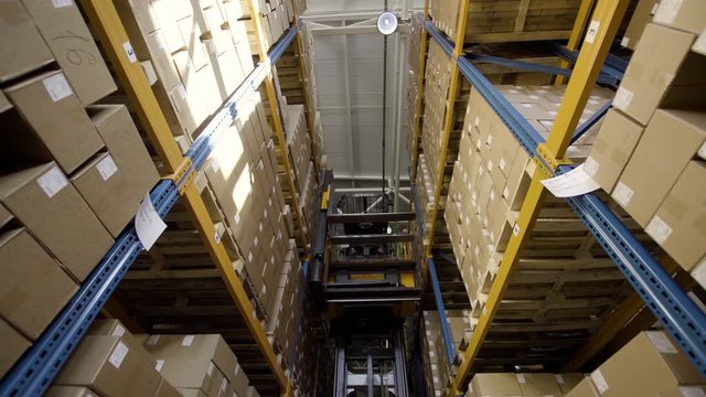 forklift moving pallets with cardboard boxes in a warehouse with high-bay boxed racks medical industry