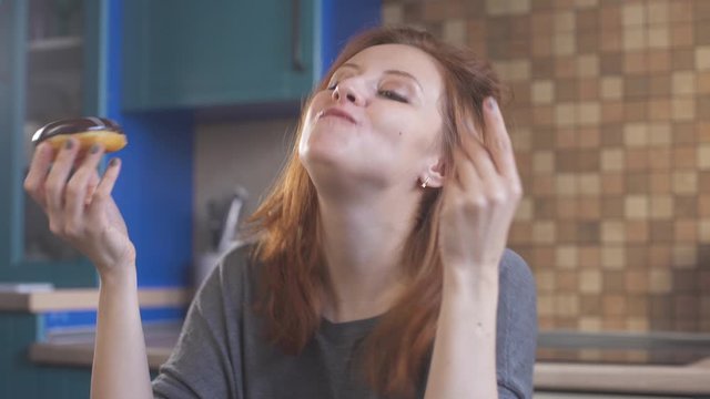 Hungry girl with red hair eating a donut. Уoung redhead woman enjoying a food. Hipster girl eating dessert, biting pice of sweet donut. Delicious food. Unhealthy nutrition. Female mouth. Close up.