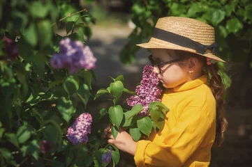 Foto op Canvas Portrait of a little girl in a straw hat with lilac © fisher05