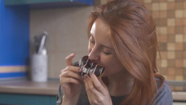 Hungry girl with red hair eating a donut. Уoung redhead woman enjoying a food. Hipster girl eating dessert, biting pice of sweet donut. Delicious food. Unhealthy nutrition. Female mouth. Close up.