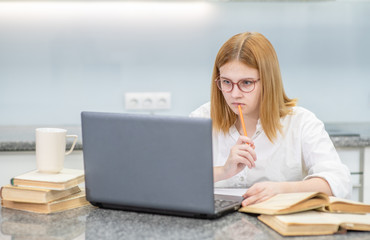 Fototapeta premium Teen girl doing homework with laptop. Distance learning concept