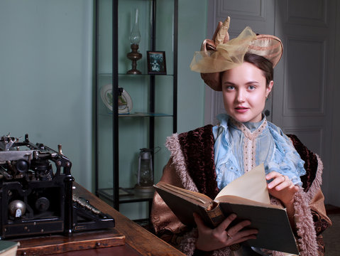 Young woman in blue vintage dress late 19th century reading the book in retro room