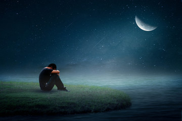 Obraz na płótnie Canvas A young man sitting alone on the moon