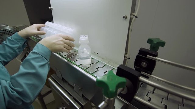 operator controls the quality and rejects non-standard bottles on Medical Solutions Conveyor. Blow fill seal technology technique used to produce liquid-filled container on medical industrial factory