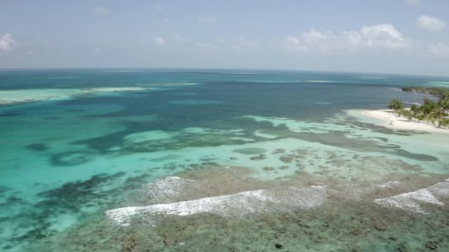 Aerial footage of Idyllic turquoise sea against sky, drone moving over waves during sunny day - Coco Plum Cay, Belize