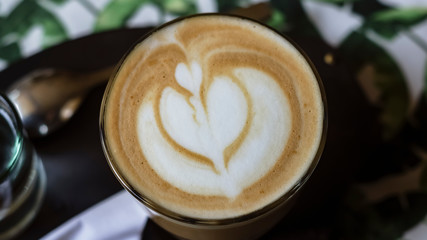 Beautiful cappuccino with foam on which the pattern on the table in a cafe