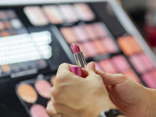 Testing colour of lipstick at cosmetic shop 