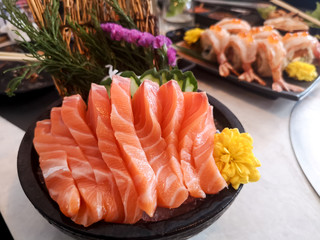 Close up juicy yummy delicious tasty raw and fresh fatty Sliced ​​orange salmon sashimi fish  in Japanese style popular seafood in black plate eat with fresh wasabi .