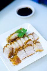 Close up and selective focus deep fried delicious yummy tasty homemade sliced Crispy pork belly roasted in white plate with sweet sour sauce on white background , Thai traditional food.
