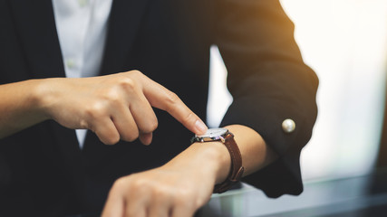 A business woman pointing at a wristwatch on her working time while waiting for someone in office