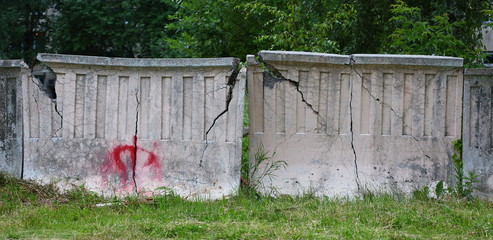 Old grey concrete cracked fence on green grass