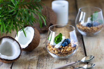 A glass of healthy breakfast: granola with fresh blueberries, coconut chips and mint.