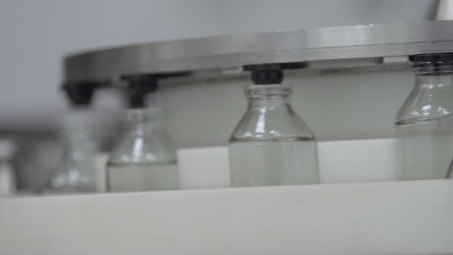 glass bottles filled and sealed with rubber caps on a medical solution conveyor line close up medical industry