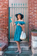 Young and beautiful brunette girl in dress and hat walking outdoor in the street. Nice, France. Summer vacation, traveling and tourism. © Acronym