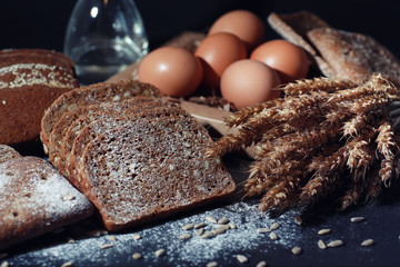 Fresh loaves of bread with wheat and gluten on a black table. Bakery and grocery concept. Fresh,...