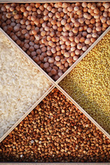 A set of grain cereals. Rice, buckwheat and millet groats in a wooden tray. A grocery set of cereals. Import of grain.
