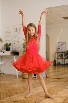  girl with long hair in red ball gown is dancing on quarantine of coronavirus at home in room