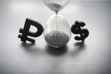 The concept of the passage of time. Hourglass on a dark background. Inscription time. The shadow on the surface of the word.