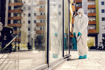 Man in sterile protective suit sterilizing outdoors from corona virus/ covid-19.