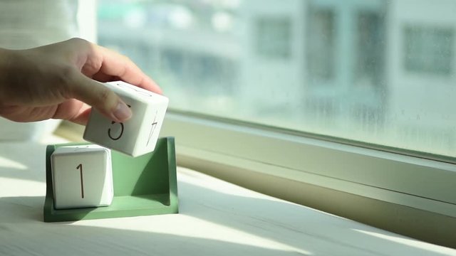 Hand changing white wooden calendar block from 14 to 15 for new day on sweet romantic pink bed with fresh morning light from modern window, concept start life motivation
