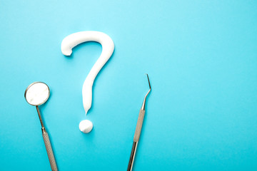 Dental instruments and white question mark on blue. Tooth treatment concept. Toothpaste question...