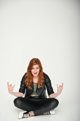 Young woman shows emotions changing poses while sitting on the floor. Portrait of a pretty girl with beautiful hair in a green T-shirt and black clothes on a white background.