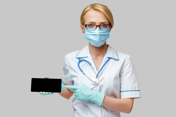 medical doctor nurse woman wearing protective mask and gloves - using mobile phone