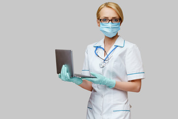 medical doctor nurse woman wearing protective mask and gloves - holding laptop