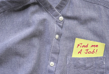 Find me a job, words in blue on a yellow paper stuck out from blue grey shirt pocket.