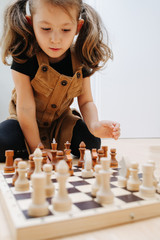 Point of view on a little girl playing chess on a kitchen floor at home