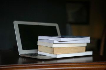 Books on top of computer laptop. Online education.