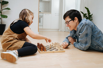 Father and little daughter playing chess on a kitchen floor at home