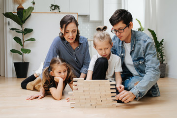Family playing muscle control and logic game, building things with wooden blocks
