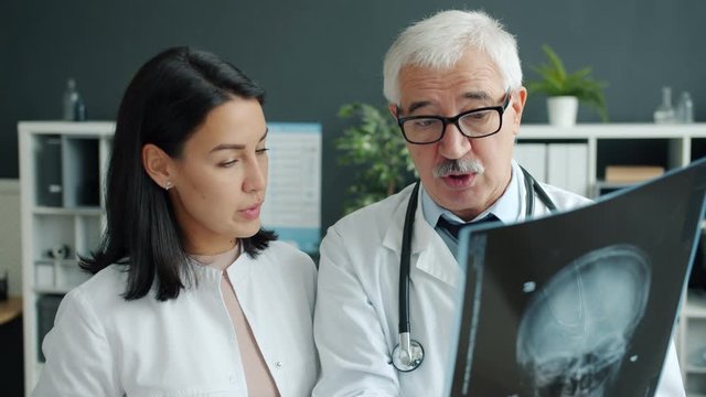 Man and woman doctors working in hospital discussing x-ray image smiling indoors in clinic office. Cooperation, medicine and patient examination concept.