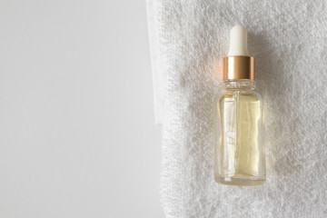 Oil serum essence dropper on towels on white background with copy space. Close-up beauty product for facial skin care, top view