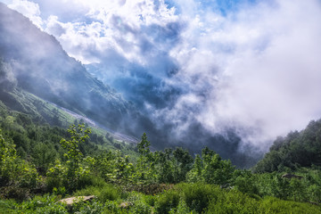 Heavy fog and clouds in mountain gorge in the summer or spring. A layer of melting snow in the...