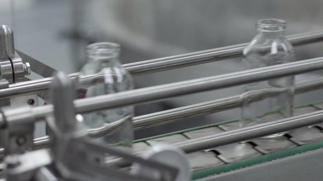 glass bottles on medical solution conveyor line close up selective focus medical industry